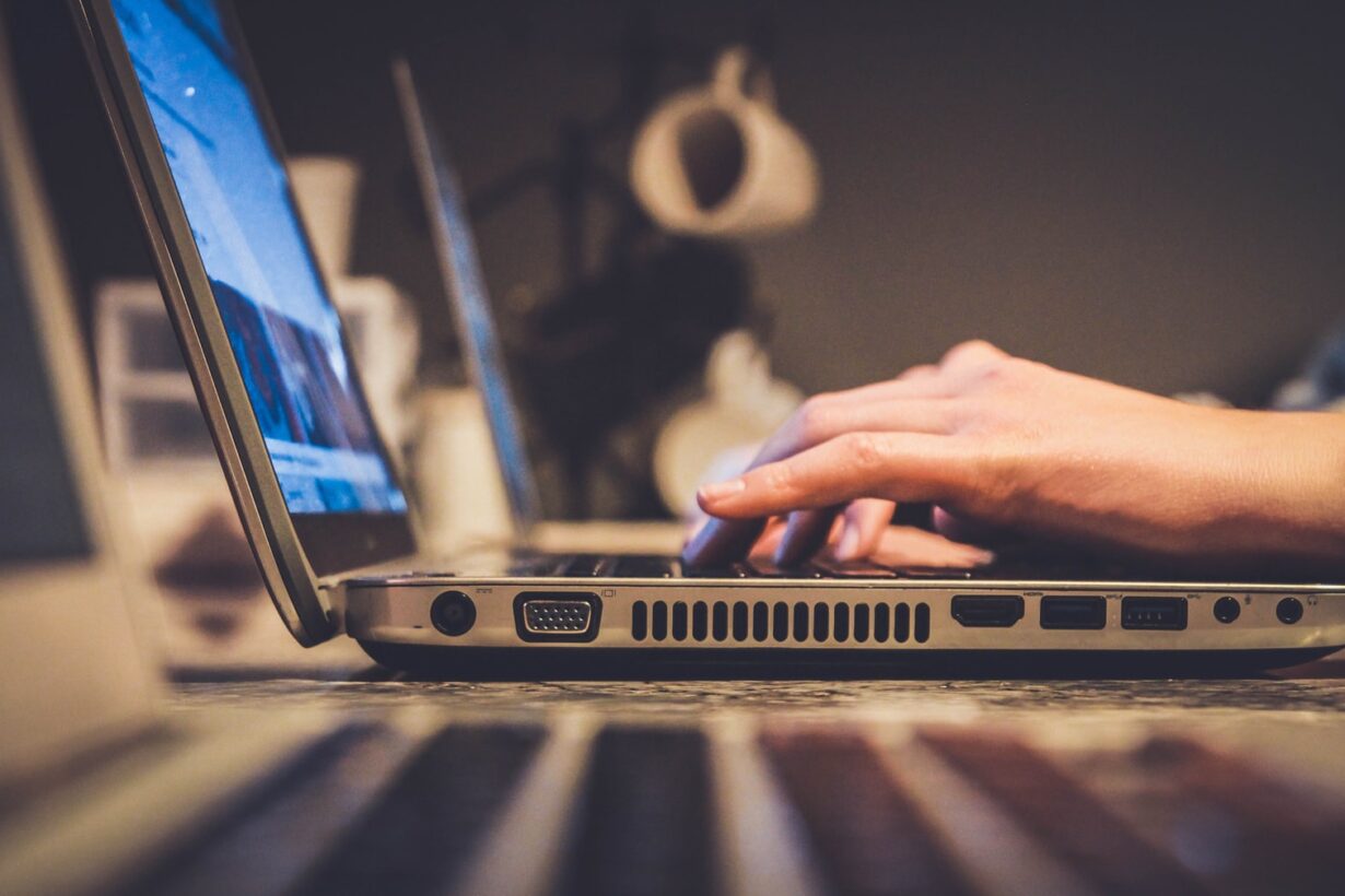 person using silver laptop computer on desk